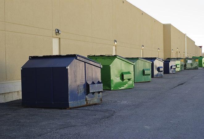 a row of yellow and blue dumpsters at a construction site in Malden